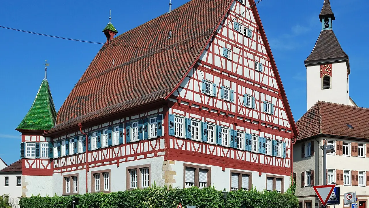 Fachwerk-Rathaus in Münchingen, Stadtteil von Korntal-Münchingen, mit Kirchturm dahinter
