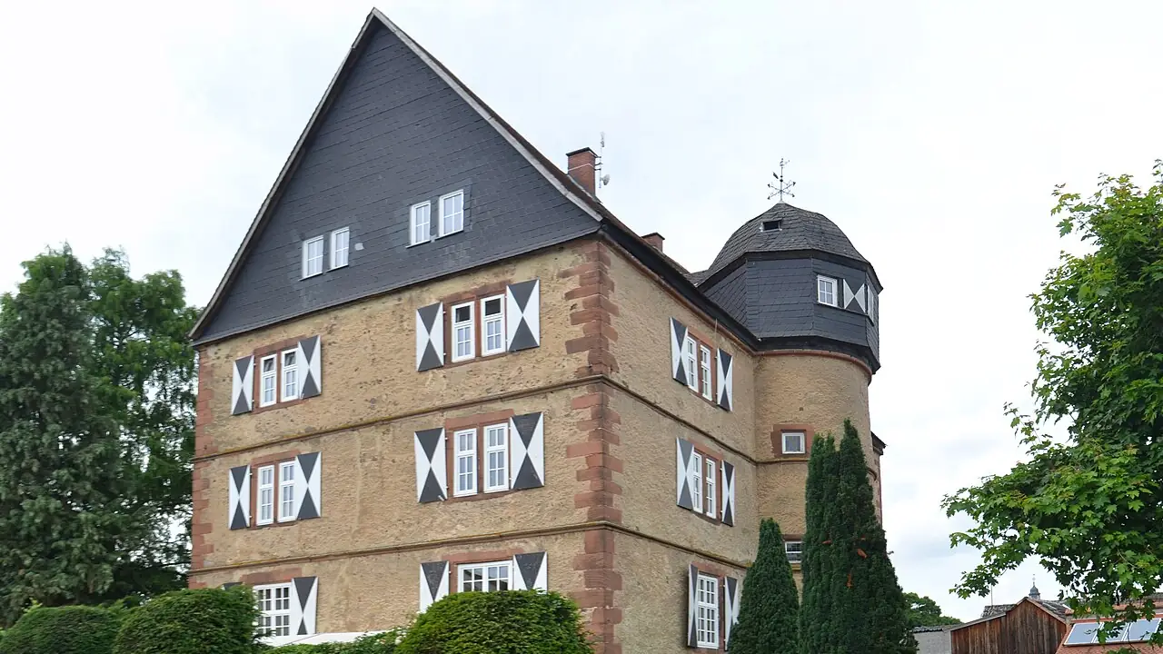 Schloss Stammheim mit Treppengiebel und Rundturm hinter einer Hecke